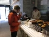 A person stands at a food counter sipping from a cup.