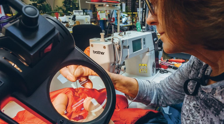 Susan Baker repairs a jacket that might just belong to her daughter, whom she raised skiing in the nearby Sierra. Photo: Ken Etzel