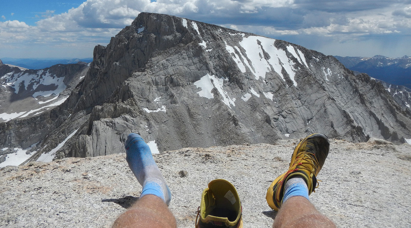 Emptying rocks from the shoes atop Mt. Russell, with a view a Mt. Whitney. Photo: Erik Schulte