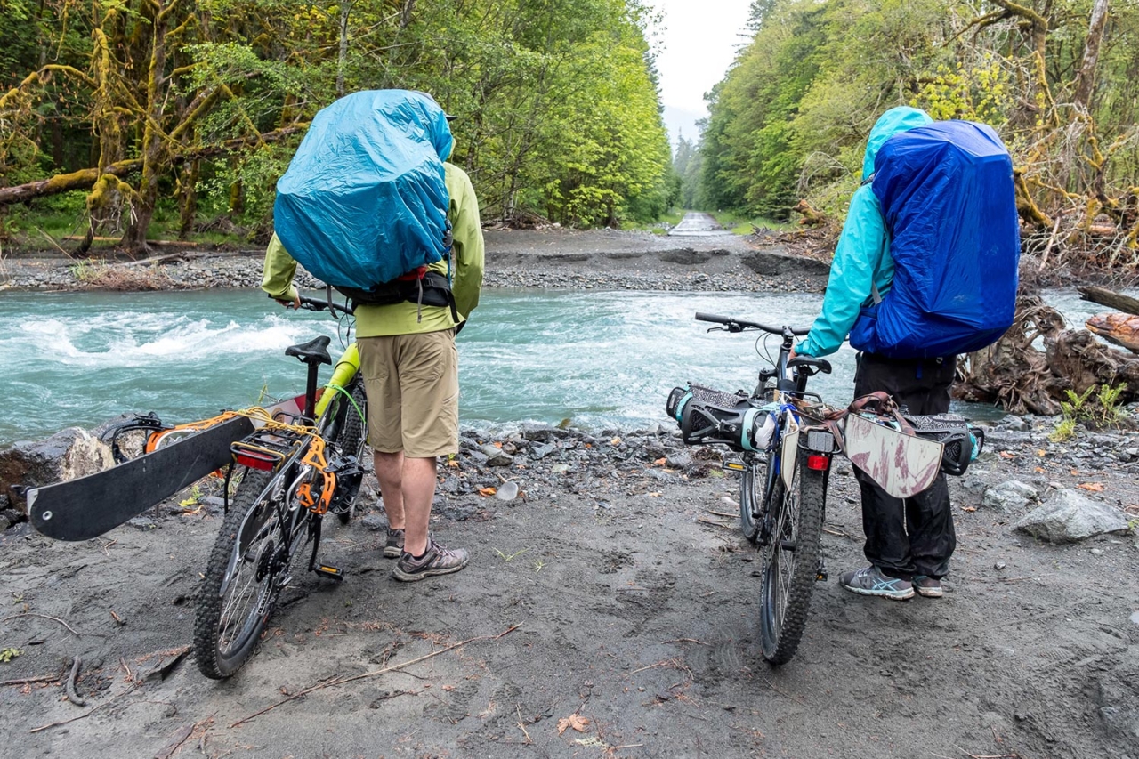 Wild rivers will do wild things. Marie-France Roy and Kael Martin contemplate a major road blow-out along the Elwha River and potential end to the bike-assisted portion of their approach to Mount Olympus. Photo: Colin Wiseman