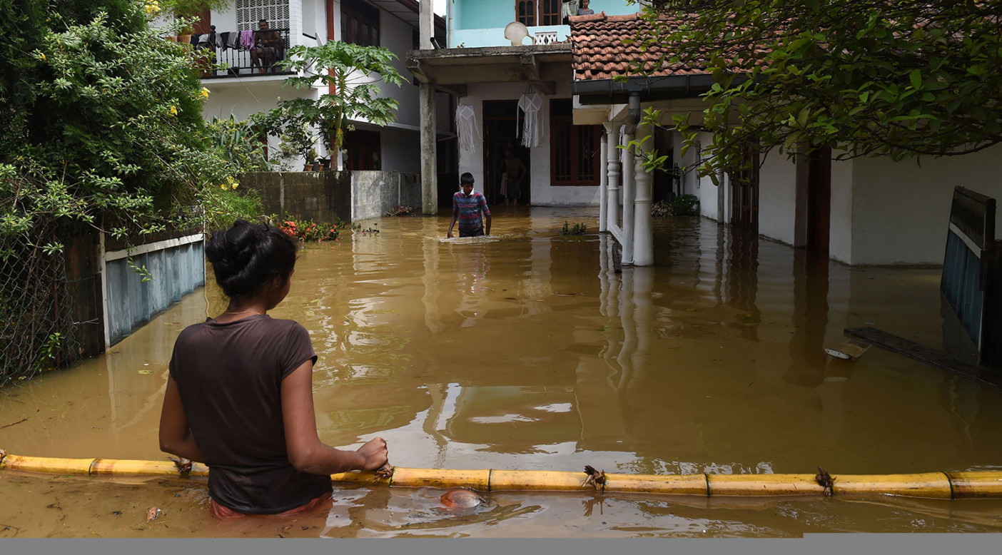 Sri Lankans outside flooded homes in Kaduwela. The massive storm that hit Sri Lanka in May of 2017 triggered the worst flooding and landslides in 14 years in the southern and western parts of the island. Extreme weather events like this one are increasing in number and strength due to human-caused climate change. Photo: Ishara S. Kodikara/AFP/Getty Images