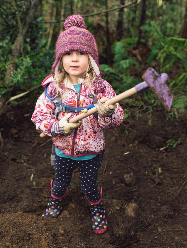 Teach ’em young. Wielding her own purple-painted hoe and rubber boots, Cloe Brown helps her dad during a trail day on Galbraith. The bimonthly work parties regularly draw dozens of volunteers, including families and riders of all ages. Photo: Paris Gore