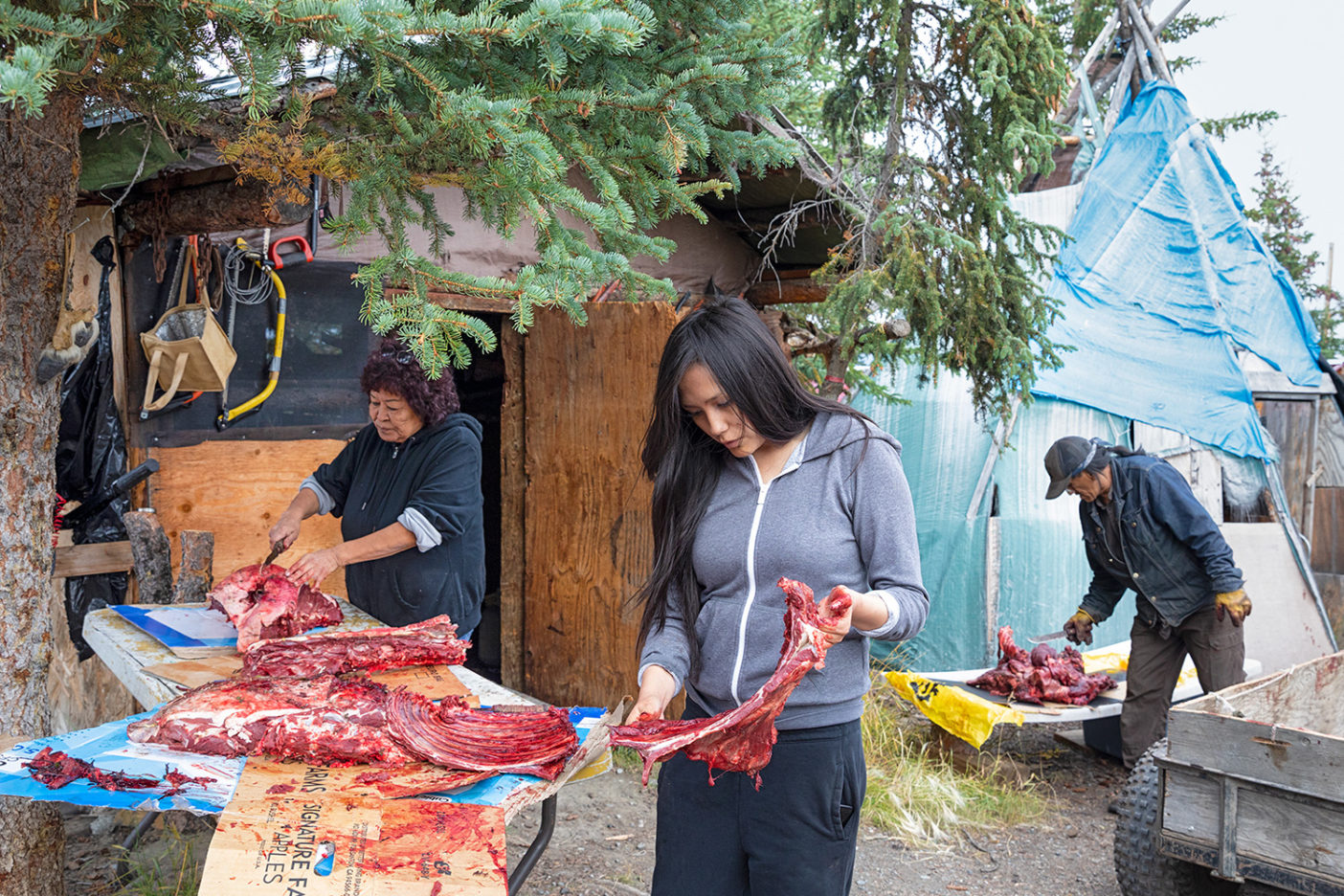 The Gilbert family and friends cut up caribou meat at their home in Vashrąįį K’ǫǫ, Alaska. Opening up the Refuge to extractive industries threatens this Gwich’in tradition. Photo: Keri Oberly