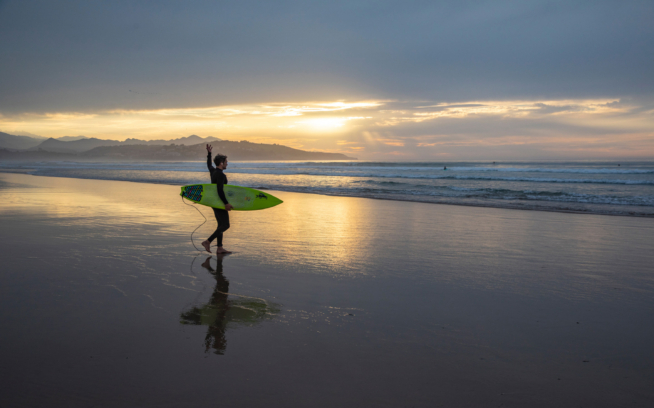 A surfer walking into the ocean.