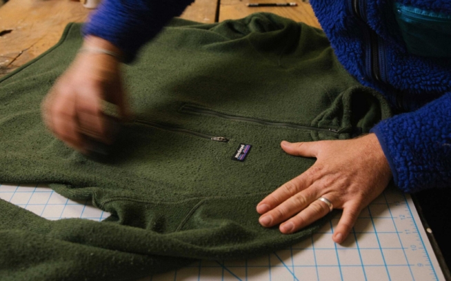 Watch the video. A person runs a fabric stone over the surface of a sweater.